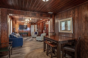 A wooden interior with a sofa, a dining table, and a TV. - Pet-Friendly Gulf-Front 3BR with Screened Porch (Alligator Point)