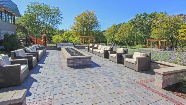 An outdoor patio with stone flooring, multiple seating areas, and a central fire feature. - Modern Lake Geneva Condo With Views (Lake Geneva)