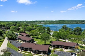 A residential area with multiple two-story buildings, a parking lot, and a body of water in the background. - Modern Lake Geneva Condo With Views (Lake Geneva)