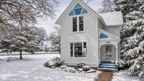 A two-story house with a number 106 on the front door, surrounded by snow-covered trees and a brick pathway leading to the entrance. - Walk to Lake Relaxing Williams Bay Getaway (Williams Bay)