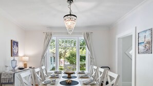 A dining area with a chandelier, white furniture, and a view through large windows. - Walk to Lake Relaxing Williams Bay Getaway (Williams Bay)