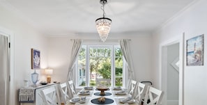 Ein Esszimmer mit einer Chandelier, einem Tisch für sechs Personen und Blick durch ein großes Fenster.