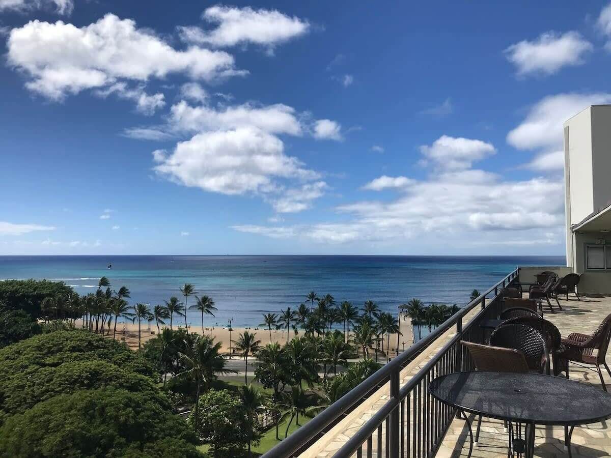 Uma varanda com vista para a praia e o oceano, equipada com mobiliário para área externa.