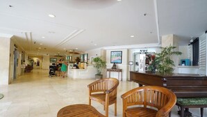 Eine geräumige Lobby mit Holzsesseln und einem Empfangsbereich.