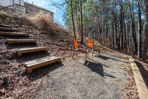 A set of wooden steps leading up to a bench in a forested area with a building in the background. - Modern 3-br Townhome w Private Backyard Near RTP (Morrisville)