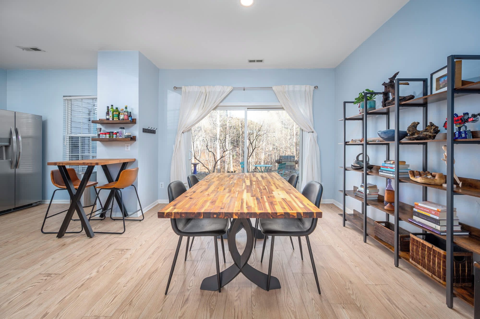 Una cocina moderna con una mesa de comedor de madera, sillas y una estantería empotrada.