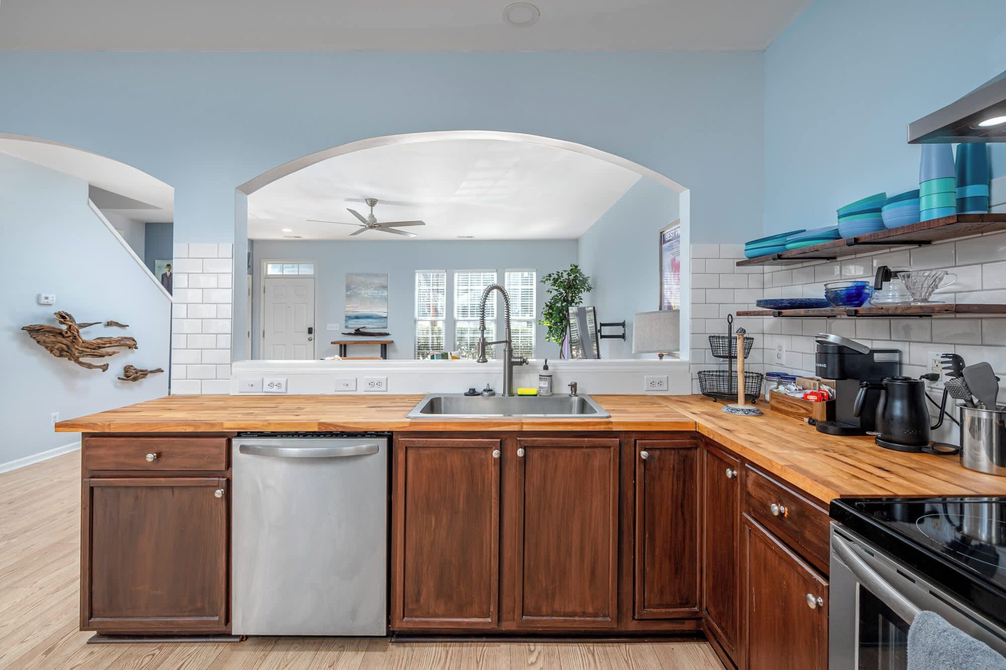 A kitchen with a wooden island, stainless steel appliances, and a view to the living area.