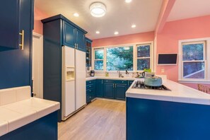 Una cocina moderna con armarios azul oscuro, una encimera blanca y una ventana con vistas a árboles.