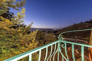 A balcony with a view of a town and hills.