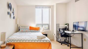 Un dormitorio con cama, escritorio, televisor y ventana.