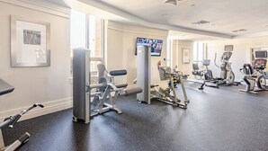 A gym with various exercise machines, a television, and a large window providing natural light. - Downtown Silver Spring 2BR Skyline Balcony Suite Walkable to DC Metro Luxepad (Silver Spring)