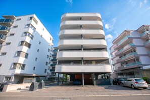 A modern multi-story building with a unique cylindrical design, surrounded by other residential buildings. - Urban Maggiolina Sunset with Terrace & Mountain Views, Locarno, Switzerland (Locarno)