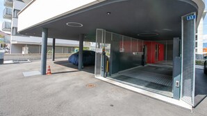 En modern entré till en byggnad med ett överbyggt område, en grind av metall och ett nummerskylt.