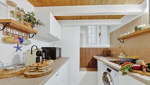 A compact kitchen with a washing machine, a coffee maker, and a shelf with jars and plants. - Festival Riviera House Sanremo Old Town Sleeps 4, Sanremo, Italy (Sanremo)