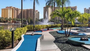 A landscaped pool area with a fountain, palm trees, and a view of high-rise buildings. - Spend the 4th of July at the beautiful Bonnet Creek Reaort in Orlando Florida (Lake Buena Vista)