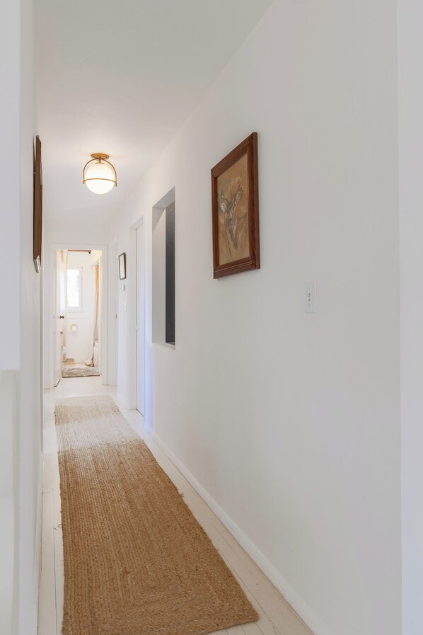 A hallway with a rug, a ceiling light, and a framed picture on the wall. - The Fesh Coast Cabin- pet friendly- hot tub (South Haven)