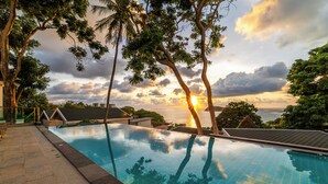 Une piscine avec vue sur le coucher de soleil et les arbres.
