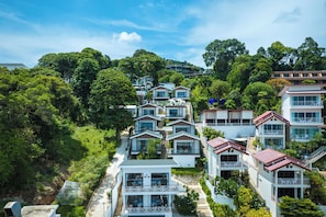 Un barrio residencial en una ladera con varias casas de dos pisos, cada una con balcones y ventanas amplias.