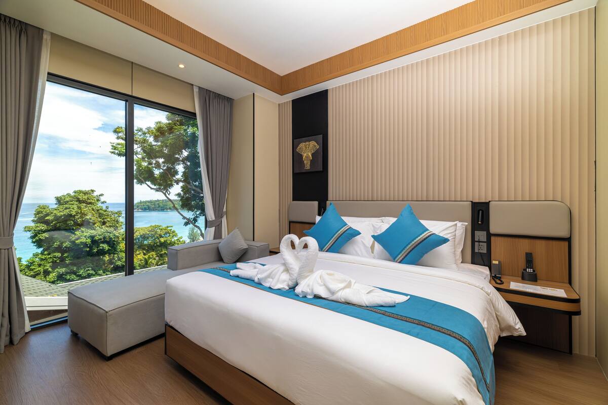 Habitación de hotel moderna con una cama grande, una mesita de noche y vistas al exterior.