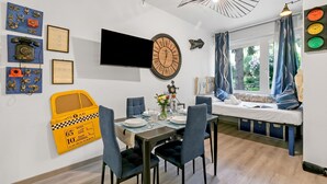 A modern room with a dining table, chairs, a bed with a view, a wall clock, and various wall decorations. - Apt Suite 125 shared pool & sun terrace, Gardone Riviera, Italy (Gardone Riviera)