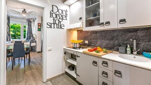 A modern kitchen with white cabinets, a marble backsplash, and a dining area with a view. - Apt Suite 125 shared pool & sun terrace, Gardone Riviera, Italy (Gardone Riviera)