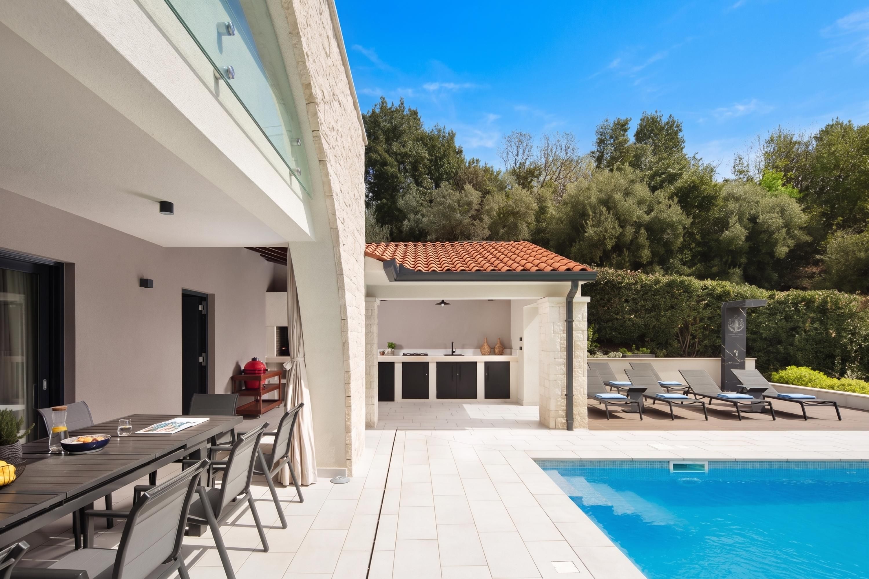 Un espace piscine extérieur moderne, aménagé avec un coin repas et un espace barbecue.