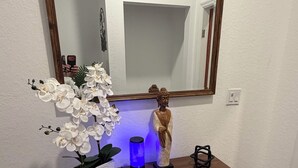 Puisesta konsolipöydästä löytyy Buddha-patsas, ruukkuorkidea ja sinisellä valolla valaistu esine.