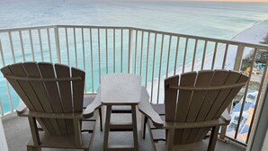 A balcony with two Adirondack chairs and a small table, overlooking a beach and ocean. - Golden Hour Penthouse  -  Beach Front,  2 BR/2 Bath Penthouse (Panama City Beach)