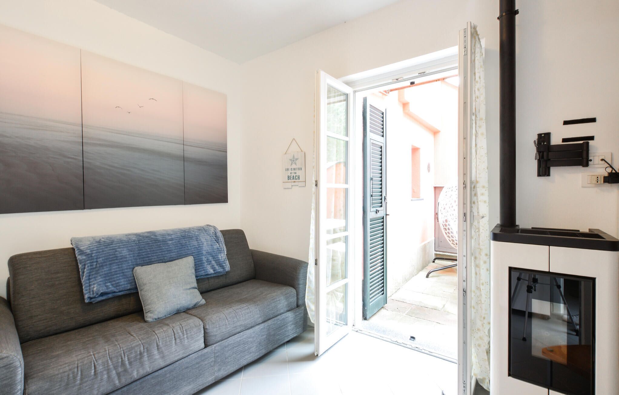 Una sala de estar moderna con un sofá gris, un cuadro abstracto grande y un ventanal corredero que da a un área exterior.
