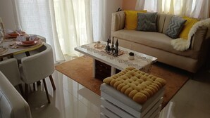 A living room with a sofa, ottoman, dining table set, and decorative items. - Vacation in punta cana (Punta Cana)