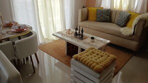 Ein Wohnzimmer mit Sofa, Hocker, Esstisch und Dekoration.