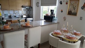 A kitchen with a dining area set for a meal, featuring a stove, sink, and window with a view. - Vacation in punta cana (Punta Cana)