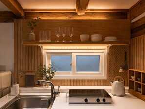 A kitchen with a wooden ceiling, a window, a sink, a stove, and a kettle. - Bukchon Hanok detached house - Old Palace, Inwangsan Mt - Garden and Tradition (Seoul)