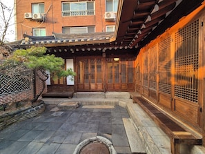 Ein traditionelles japanisches Gebäude mit einem Ziegeldach, Holztüren und einem mit Steinen gepflasterten Innenhof.