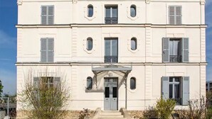 En toetages bygning med en symmetrisk facade, en midterliggende indgang med trapper og jævnt placerede vinduer.