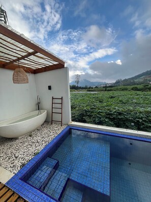 A modern outdoor pool with blue tiles, a white freestanding tub, and a wooden ceiling structure. - The Ridge Villas by Royal Cabin Dieng (Dieng Kulon)