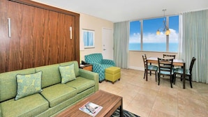 A living room with a sofa, ottoman, dining table, chairs, and a view of the sea. - Cozy Studio condo with AC in amazing Hollywood (Hollywood)
