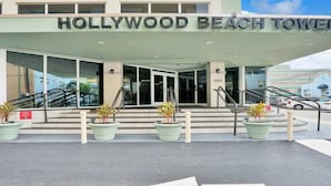 The Hollywood Beach Tower entrance with a clear view of the building's name, a set of stairs leading up to the entrance, and directional arrows on the ground. - Cozy Studio condo with AC in amazing Hollywood (Hollywood)