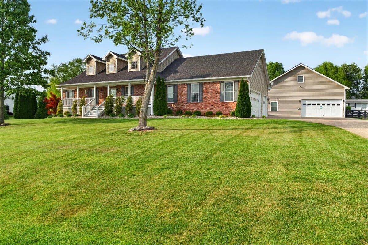 A two-story house with a front porch, a garage, and a well-maintained lawn.