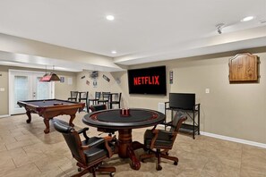 A room with a pool table, a round table with chairs, a television, and a cabinet. - Exclusive Buckner retreat w/ theater & game room! (Buckner)