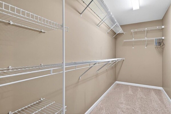 A room with beige walls, a carpeted floor, and multiple white metal shelves.