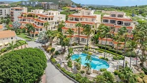 A resort with multiple-story buildings, a swimming pool, and palm trees. - Casa Piscadera · Ocean View · Pool · Beaches (Piscadera)