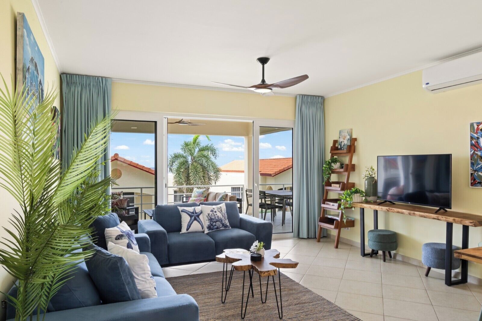 Un salon avec un canapé, une table basse, un téléviseur et un balcon offrant une vue agréable.