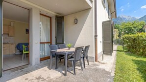 Une terrasse avec une table et des chaises, une petite plante et une vue sur les montagnes.