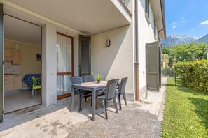 A patio with a table and chairs, a small plant, and a view of mountains. - Porto Letizia Rossini 3, Porlezza, Italy (Porlezza)