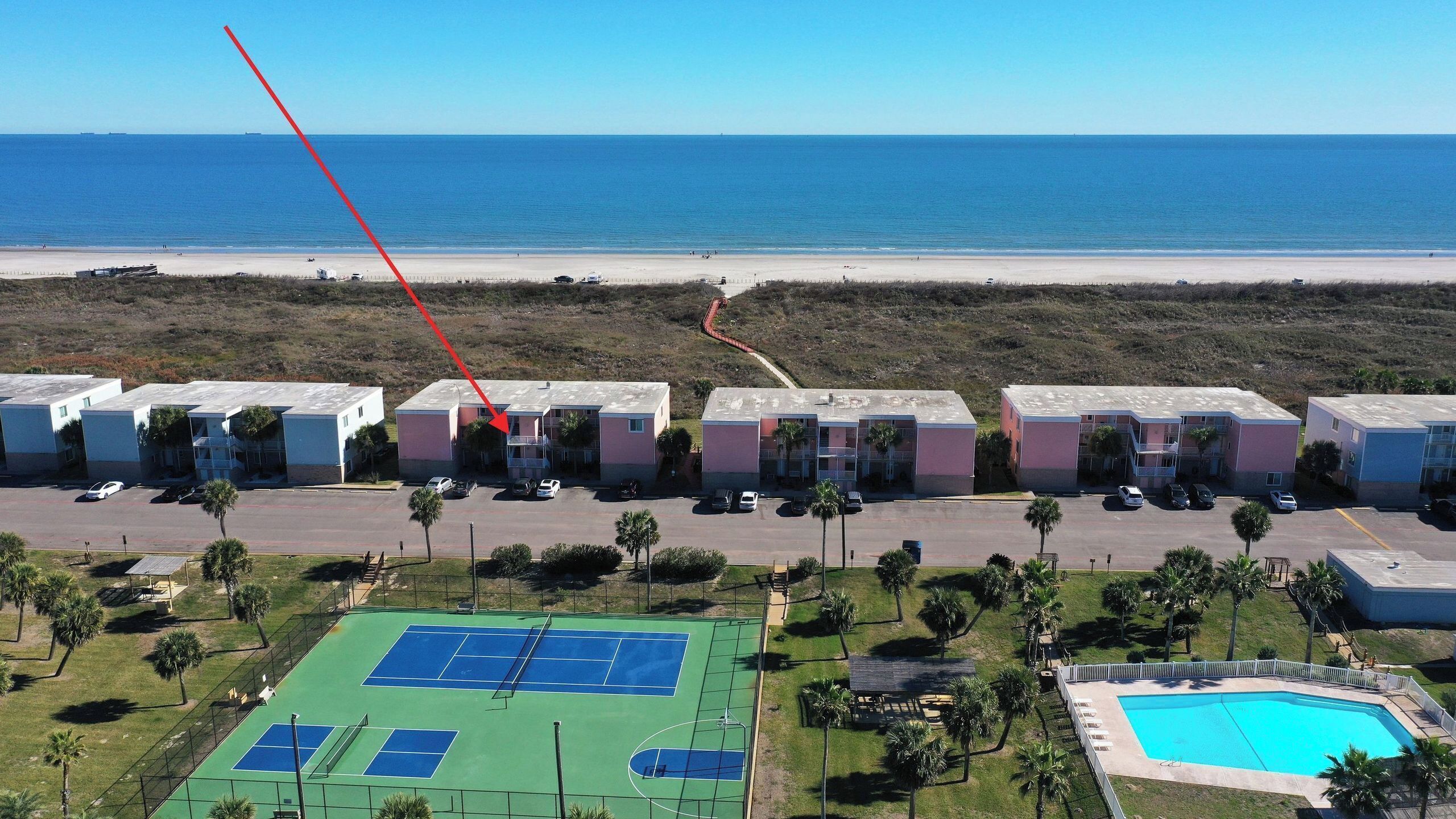 Een strandhotel met meerlaags gebouwen, een tennisbaan en een zwembad.
