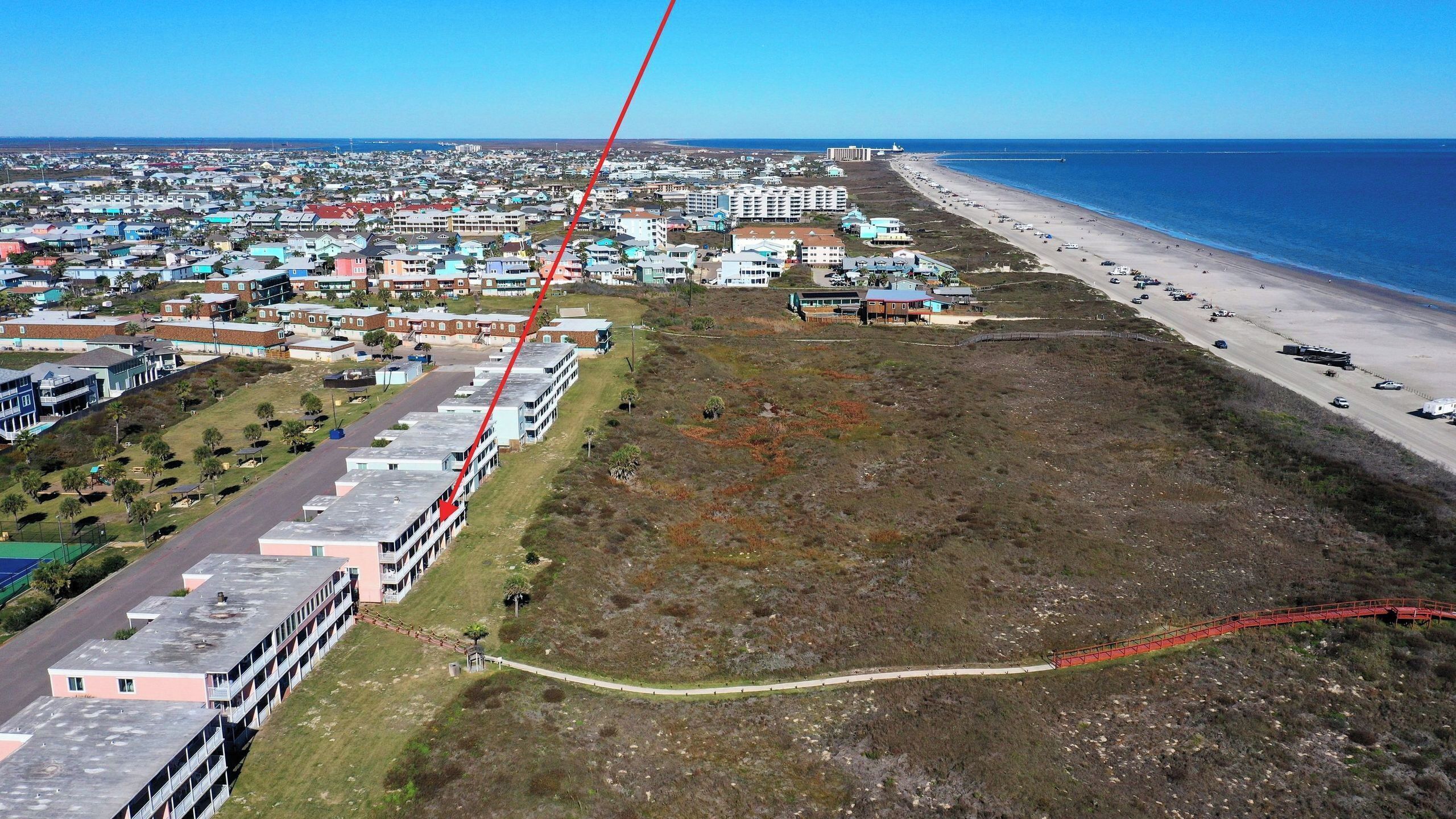 Une zone côtière comprenant une plage, une route et une rangée de bâtiments.