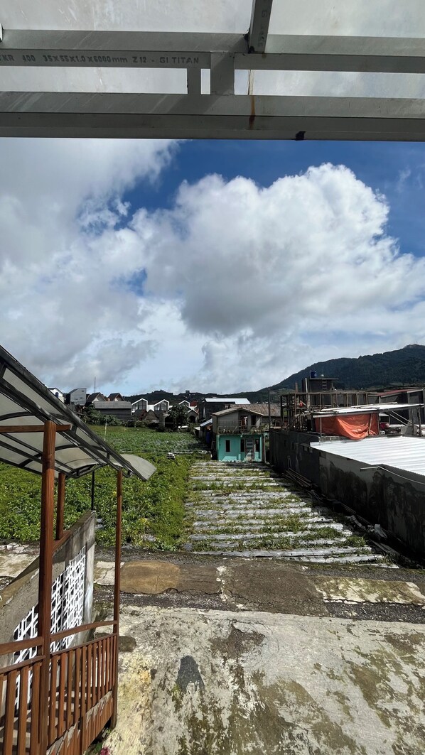 A rooftop with a view of houses and a mountain in the background. - Cabin Dieng Db (Dieng Kulon)