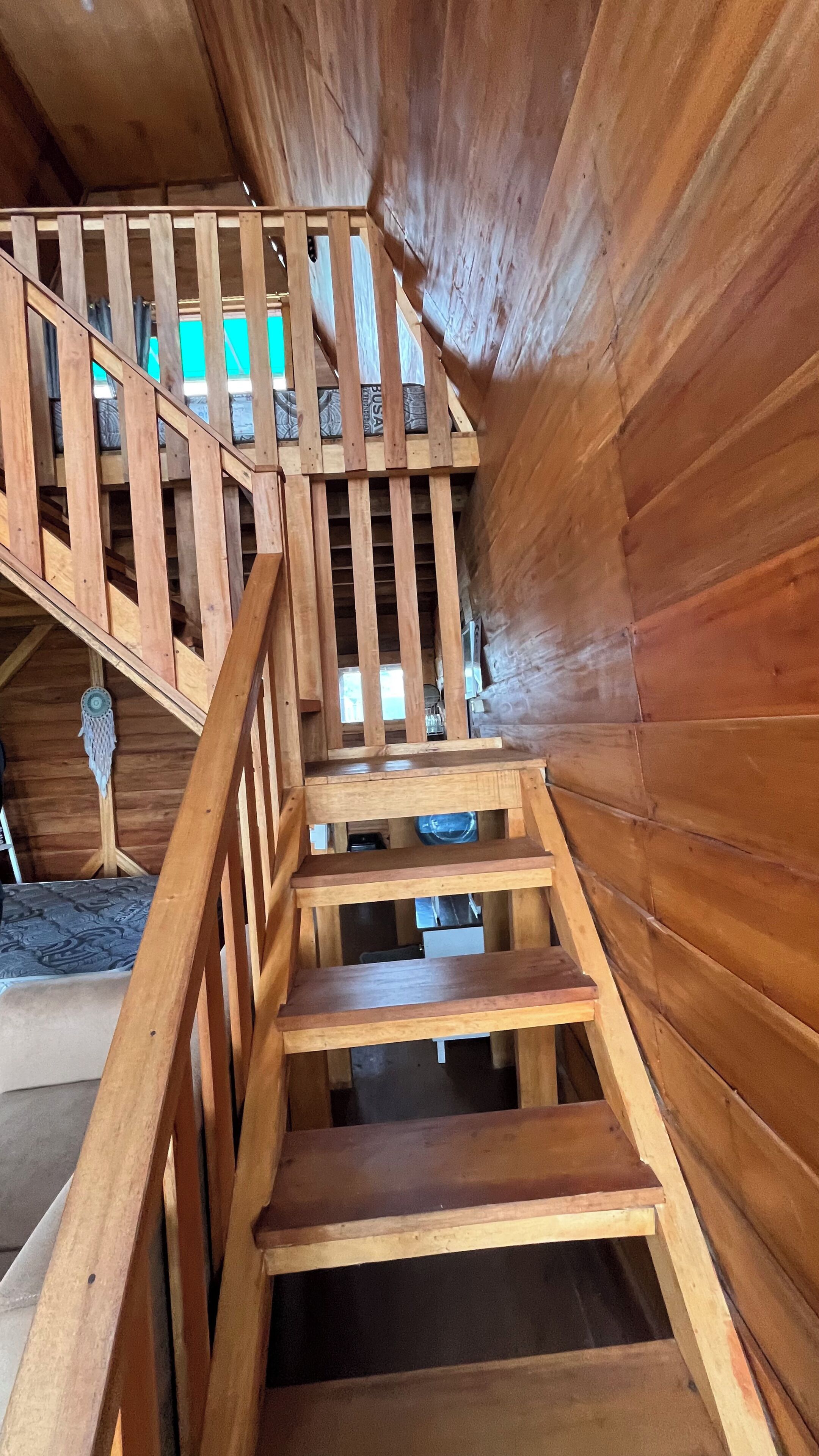 Eine Holztreppe mit Geländer, die zu einer oberen Ebene führt.