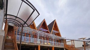 A building with a covered outdoor area, wooden staircases, and a flat roof. - Cabin Dieng Db (Dieng Kulon)